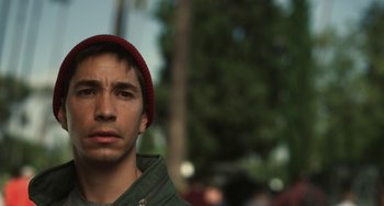 Movie still from “Comet” (2014), directed by Sam Esmail – A young man wearing a red hat is looking at the camera; Close Up shot, Low angle