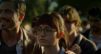 Movie still from “Comet” (2014), directed by Sam Esmail – A woman with glasses is standing in a crowd of people; Close Up shot, Over the shoulder angle