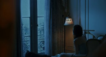 Movie still from “Comet” (2014), directed by Sam Esmail – A woman sitting on a bed in front of a window; Medium shot, High angle