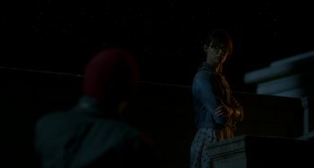 Movie still from “Comet” (2014), directed by Sam Esmail – A man standing next to another man in a dark room; Medium shot, Over the shoulder angle