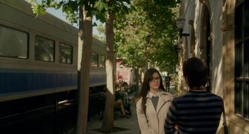 Movie still from “Comet” (2014), directed by Sam Esmail – A woman standing next to a tree on a sidewalk; Wide shot, Over the shoulder angle