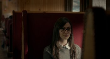 Movie still from “Comet” (2014), directed by Sam Esmail – A woman sitting on a red chair looking at the camera; Close Up shot, Over the shoulder angle