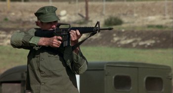 Movie still from “Coming Home” (1978), directed by Hal Ashby – A man holding a rifle and aiming it at a target; Medium shot, Low angle