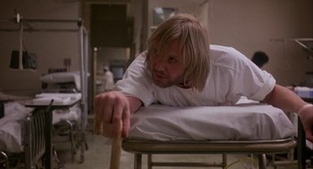 Movie still from “Coming Home” (1978), directed by Hal Ashby – A man with long blonde hair is laying on top of a hospital bed; Medium shot, Low angle