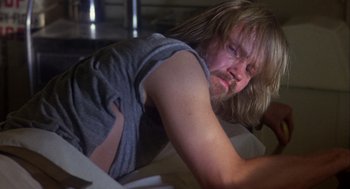 Movie still from “Coming Home” (1978), directed by Hal Ashby – A man with long blond hair is leaning on a table; Close Up shot, Low angle