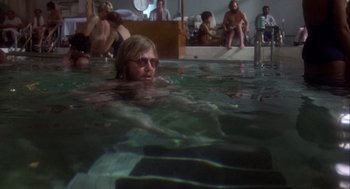 Movie still from “Coming Home” (1978), directed by Hal Ashby – A man swimming in a swimming pool while people sit in the background; Wide shot, Low angle