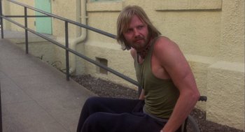 Movie still from “Coming Home” (1978), directed by Hal Ashby – A man sitting on the ground in front of a railing; Medium shot, Low angle