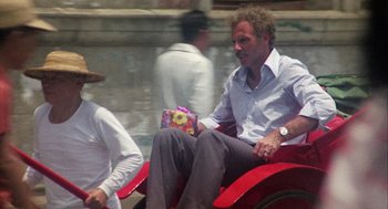 Movie still from “Coming Home” (1978), directed by Hal Ashby – A man sitting on a red carriage holding a present; Wide shot, High angle