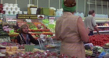 Movie still from “Coming Home” (1978), directed by Hal Ashby – A woman wearing a green hat in front of a man in front of a fruit stand; Medium shot, Over the shoulder angle
