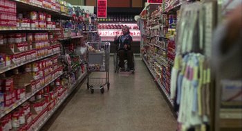 Movie still from “Coming Home” (1978), directed by Hal Ashby – A man sitting in a shopping cart in a grocery store; Wide shot, High angle