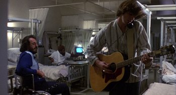 Movie still from “Coming Home” (1978), directed by Hal Ashby – A man playing a guitar in a hospital room; Medium shot, Low angle