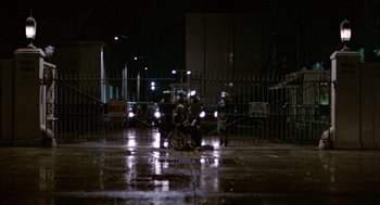 Movie still from “Coming Home” (1978), directed by Hal Ashby – A person riding a bike on a wet street; Extreme Wide shot, High angle