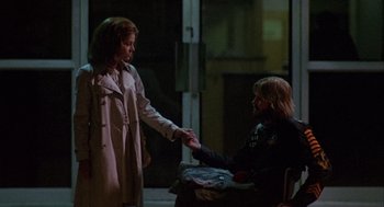 Movie still from “Coming Home” (1978), directed by Hal Ashby – A woman in a trench coat is shaking hands with a man in a black jacket; Medium shot, Over the shoulder angle