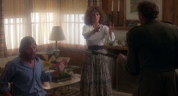 Movie still from “Coming Home” (1978), directed by Hal Ashby – A woman in a skirt is holding a sword in her hands; Medium shot, Over the shoulder angle