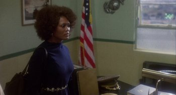 Movie still from “Coming Home” (1978), directed by Hal Ashby – A woman standing in front of an american flag in a room; Medium shot, Over the shoulder angle