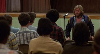 Movie still from “Coming Home” (1978), directed by Hal Ashby – A group of people sitting in front of microphones in a room; Medium shot, Over the shoulder angle
