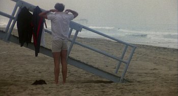 Movie still from “Coming Home” (1978), directed by Hal Ashby – A man standing on the beach next to a railing; Wide shot, Low angle