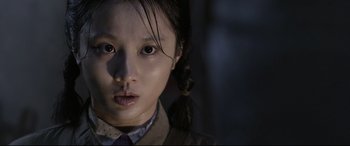 Movie still from “Coming Home” (2014), directed by Yimou Zhang – A young asian girl with a pigtail in a dark room; Close Up shot, Over the shoulder angle