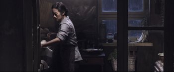 Movie still from “Coming Home” (2014), directed by Yimou Zhang – A woman in an apron standing next to a table; Medium shot, Low angle