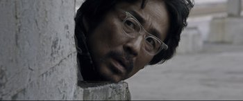 Movie still from “Coming Home” (2014), directed by Yimou Zhang – A person wearing glasses and looking at the camera; Close Up shot, Over the shoulder angle