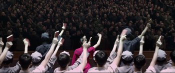 Movie still from “Coming Home” (2014), directed by Yimou Zhang – A group of people holding up their hands in front of an audience; Medium shot, High angle