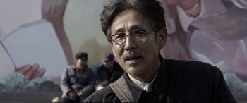 Movie still from “Coming Home” (2014), directed by Yimou Zhang – An older man wearing glasses and a black shirt; Close Up shot, Over the shoulder angle