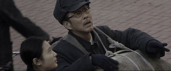 Movie still from “Coming Home” (2014), directed by Yimou Zhang – A man and a woman sitting on a brick road; Medium shot, Low angle