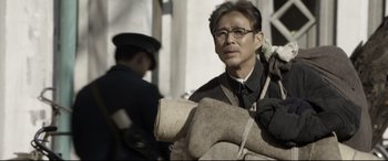 Movie still from “Coming Home” (2014), directed by Yimou Zhang – An older man wearing glasses and a black shirt; Close Up shot, Low angle