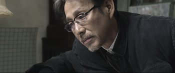 Movie still from “Coming Home” (2014), directed by Yimou Zhang – An older man wearing glasses and a black jacket; Close Up shot, Over the shoulder angle