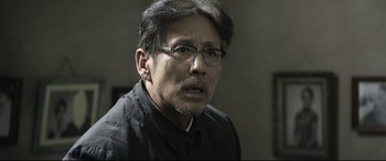 Movie still from “Coming Home” (2014), directed by Yimou Zhang – A person wearing glasses and a black shirt; Close Up shot, Over the shoulder angle