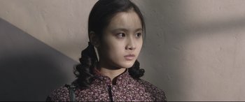 Movie still from “Coming Home” (2014), directed by Yimou Zhang – A young woman in a floral dress looking at the camera; Close Up shot, Over the shoulder angle