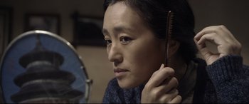 Movie still from “Coming Home” (2014), directed by Yimou Zhang – A woman holding a hair brush in her hand; Close Up shot, Over the shoulder angle