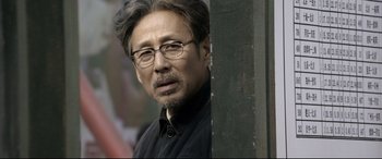 Movie still from “Coming Home” (2014), directed by Yimou Zhang – An older man wearing glasses and a black shirt; Close Up shot, Over the shoulder angle