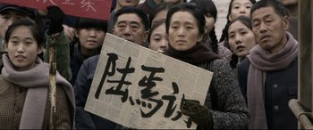 Movie still from “Coming Home” (2014), directed by Yimou Zhang – A group of people standing in a crowd holding signs; Medium shot, High angle
