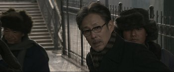 Movie still from “Coming Home” (2014), directed by Yimou Zhang – A man wearing glasses and a black jacket; Close Up shot, Over the shoulder angle