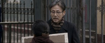 Movie still from “Coming Home” (2014), directed by Yimou Zhang – An older man wearing glasses and a scarf; Close Up shot, Over the shoulder angle