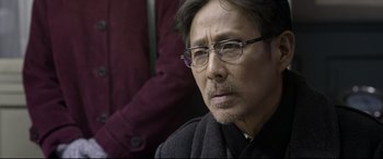 Movie still from “Coming Home” (2014), directed by Yimou Zhang – An older man wearing glasses and a black coat; Close Up shot, Over the shoulder angle