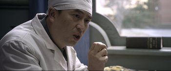Movie still from “Coming Home” (2014), directed by Yimou Zhang – A man wearing a white hat is holding his fist up; Close Up shot, Over the shoulder angle