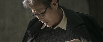 Movie still from “Coming Home” (2014), directed by Yimou Zhang – A person wearing glasses and a sweater; Close Up shot, Low angle