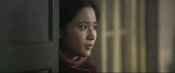 Movie still from “Coming Home” (2014), directed by Yimou Zhang – A young woman looking at the camera while standing in front of a window; Close Up shot, Over the shoulder angle