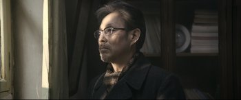 Movie still from “Coming Home” (2014), directed by Yimou Zhang – A person wearing glasses and a coat; Close Up shot, Low angle