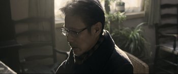 Movie still from “Coming Home” (2014), directed by Yimou Zhang – A person wearing glasses and a coat; Close Up shot, Low angle