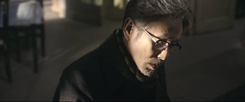 Movie still from “Coming Home” (2014), directed by Yimou Zhang – A person wearing glasses and a coat; Close Up shot, Low angle