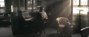 Movie still from “Coming Home” (2014), directed by Yimou Zhang – An older man sitting at a piano in a room; Wide shot, High angle