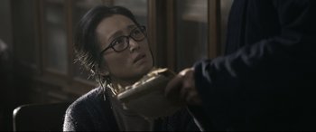 Movie still from “Coming Home” (2014), directed by Yimou Zhang – A person with glasses is holding a book; Close Up shot, Over the shoulder angle