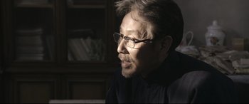 Movie still from “Coming Home” (2014), directed by Yimou Zhang – A person wearing glasses and a black shirt; Close Up shot, Over the shoulder angle