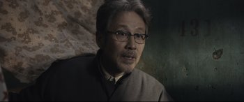 Movie still from “Coming Home” (2014), directed by Yimou Zhang – An older man wearing glasses and a gray jacket; Close Up shot, Over the shoulder angle