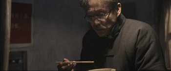 Movie still from “Coming Home” (2014), directed by Yimou Zhang – A man holding chopsticks in front of a bowl of food; Close Up shot, Low angle