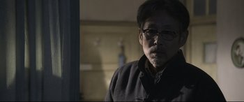 Movie still from “Coming Home” (2014), directed by Yimou Zhang – A person wearing glasses and a jacket; Close Up shot, Over the shoulder angle