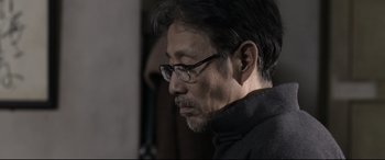 Movie still from “Coming Home” (2014), directed by Yimou Zhang – A person wearing glasses; Close Up shot, Over the shoulder angle